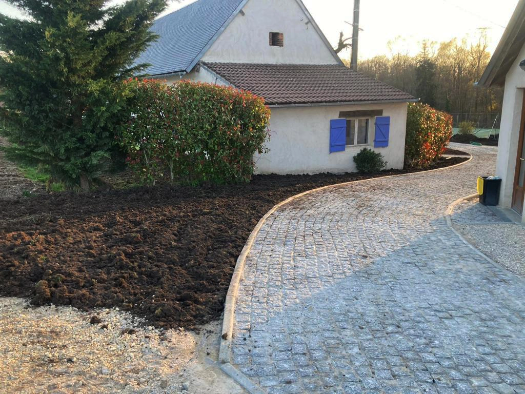 Allée pavée décrivant une courbe le long d'une haie de photinias