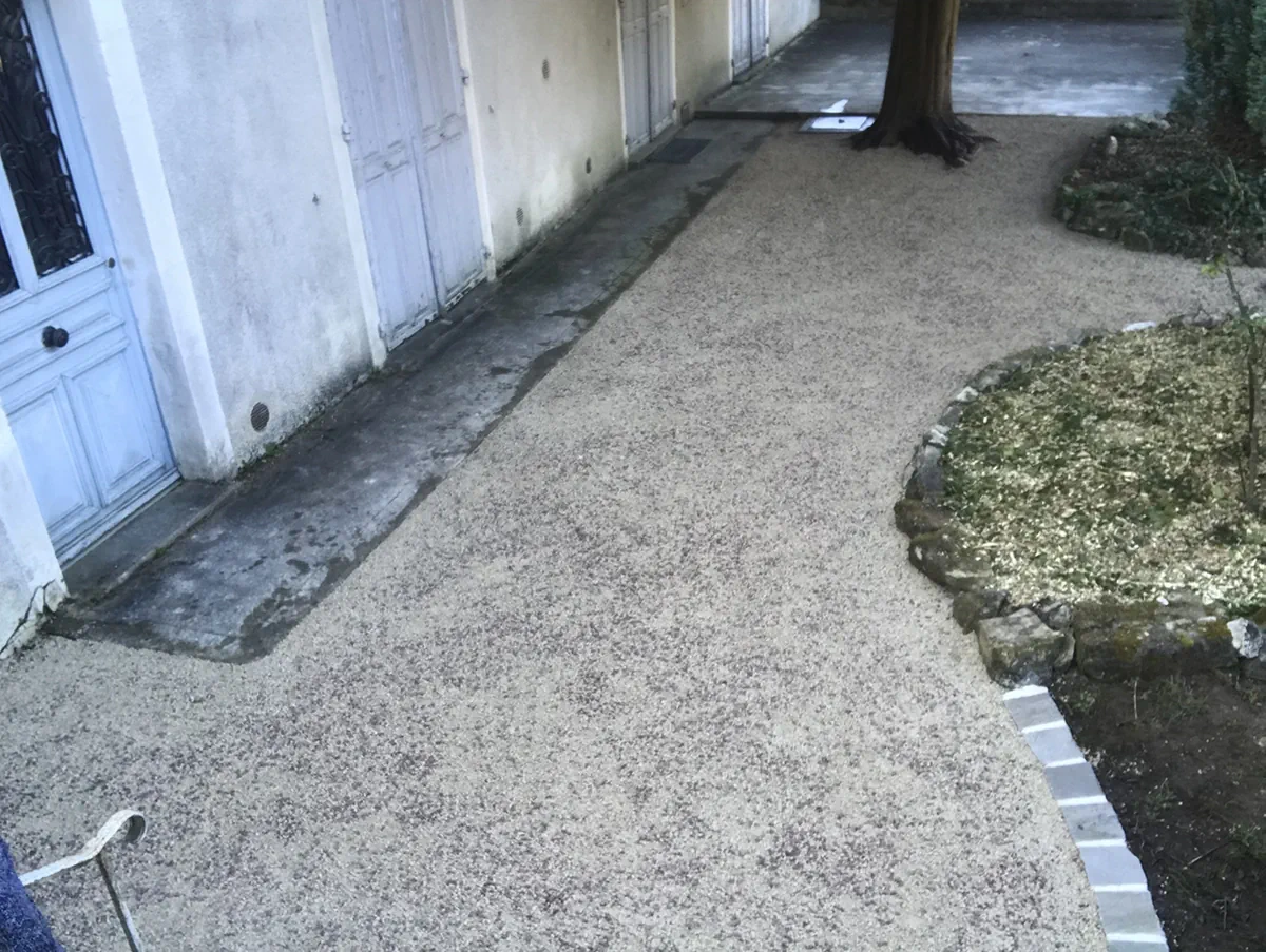 Cour en gravier stabilisé devant d'anciennes dépendances aux portes de bois