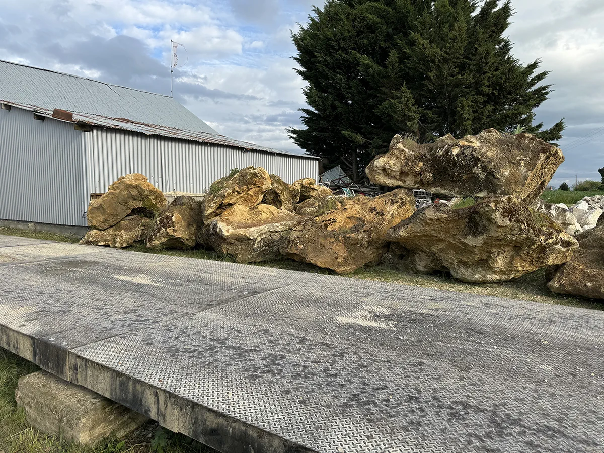 Blocs calcaires alignés le long d'un hangar, prêts à partir sur le chantier