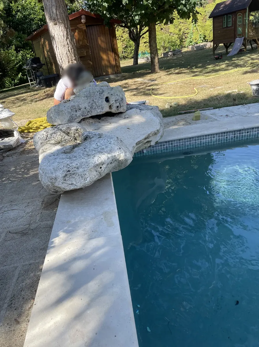 Gros blocs de pierre disposés en margelle au bord d'une piscine, sur un dallage clair