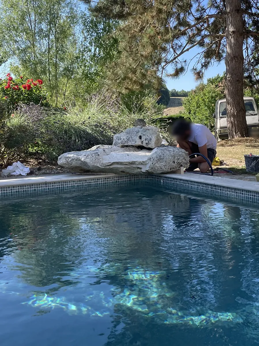 Compagnon raccordant un rocher de cascade en pierre au bord d'une piscine en eau