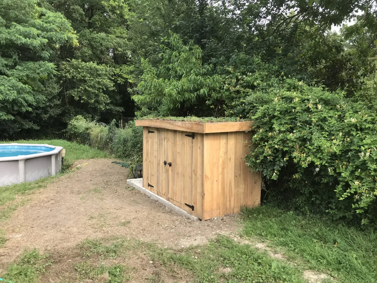 Local technique en bois coiffé d'une toiture végétalisée de sedums, au bord d'une piscine