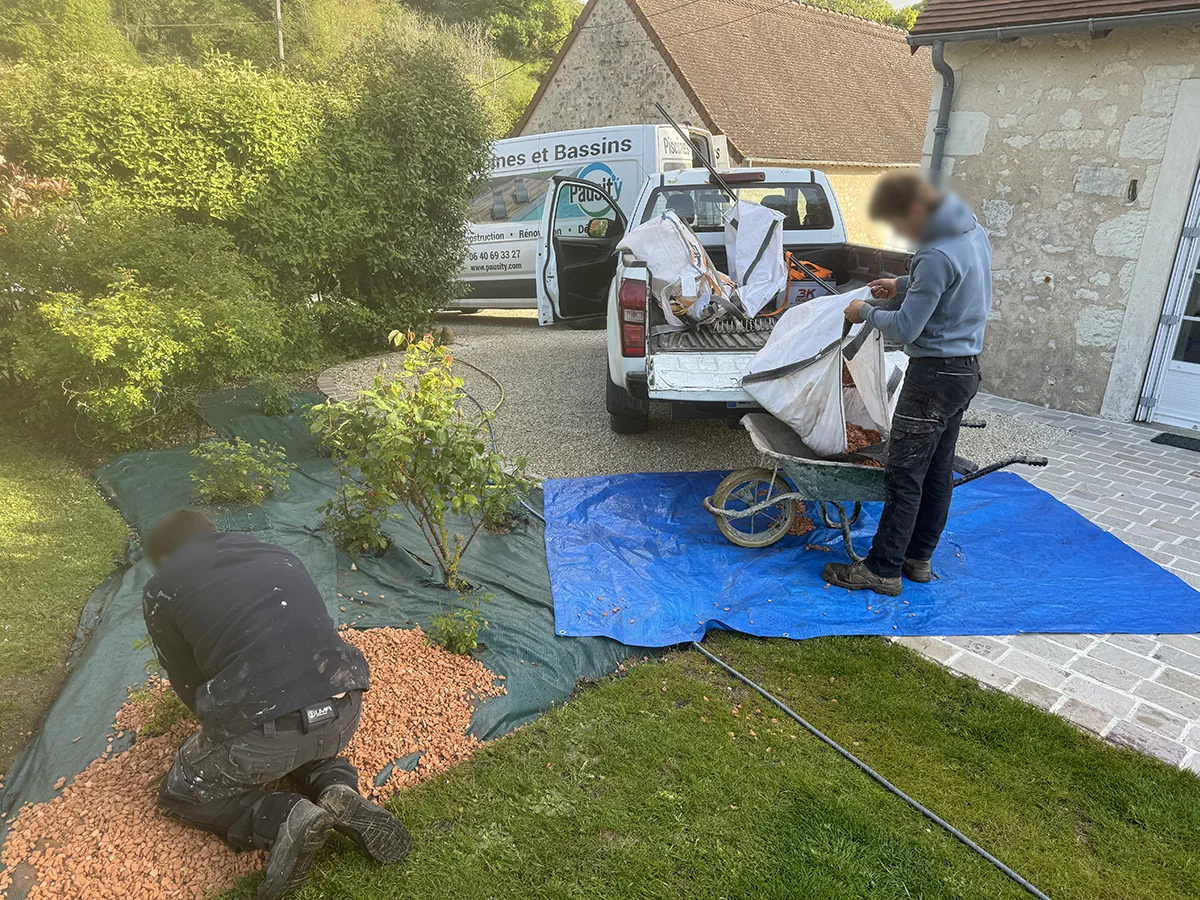 Deux compagnons étalant le paillage d'un massif, pick-up Pausity et big-bags de graviers à l'arrière