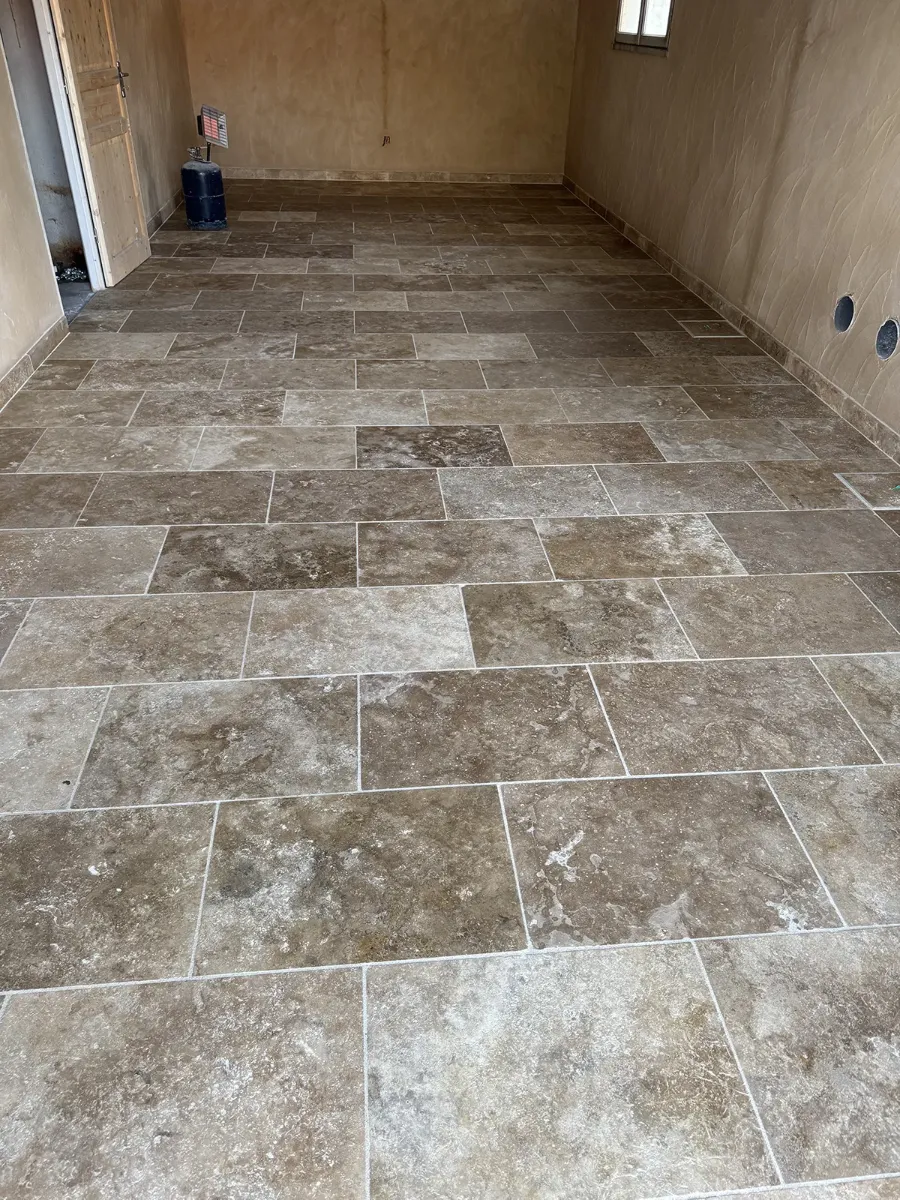 Dallage de travertin posé en opus dans une pièce en cours de rénovation, plinthes assorties