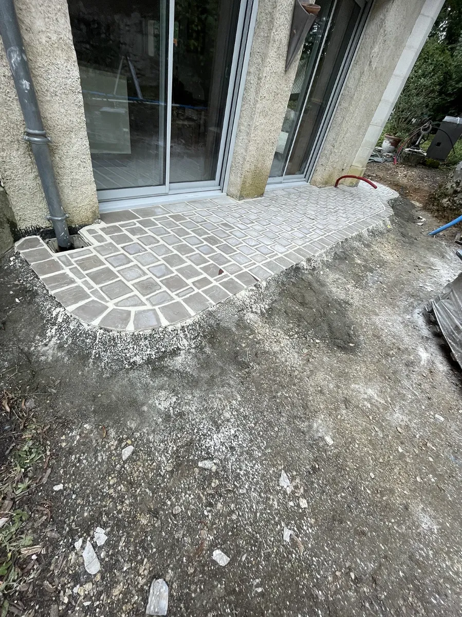 Seuil de terrasse en pavés de pierre terminé en arc de cercle, devant une baie vitrée